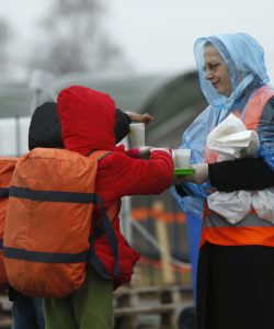 Des enfants migrants prennent des tasses de thé servies par une religieuse tandis que les migrants et les réfugiés sont enregistrés par les autorités avant de continuer leur voyage en train vers l’Europe occidentale, dans un camp de transit à Slavonski Brod, en Croatie.