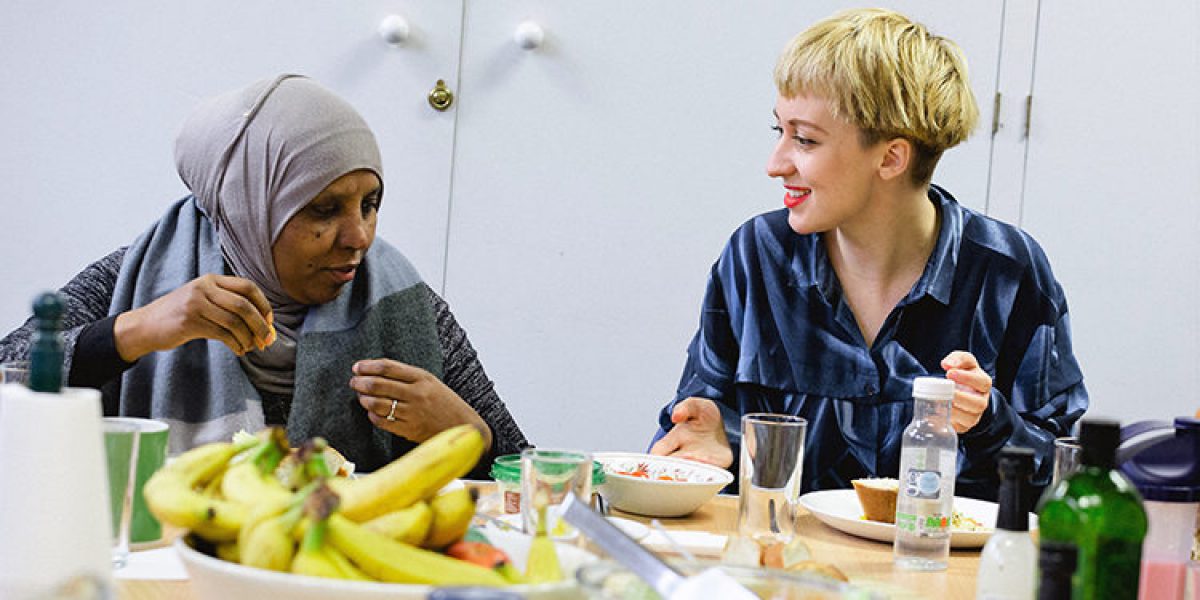 Naomi Turner, coordinadora de proyecto, habla durante el almuerzo con uno de los invitados de At Home en el centro del JRS.