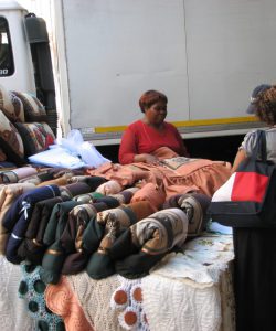 Sr. Joanne Whitaker and the JRS IGA project director speak with Martha, a Ugandan refugee woman from JRS IGA program, who markets her hand sewn pillows and spreads on street in Johannesburg, South Africa, March, 2010.