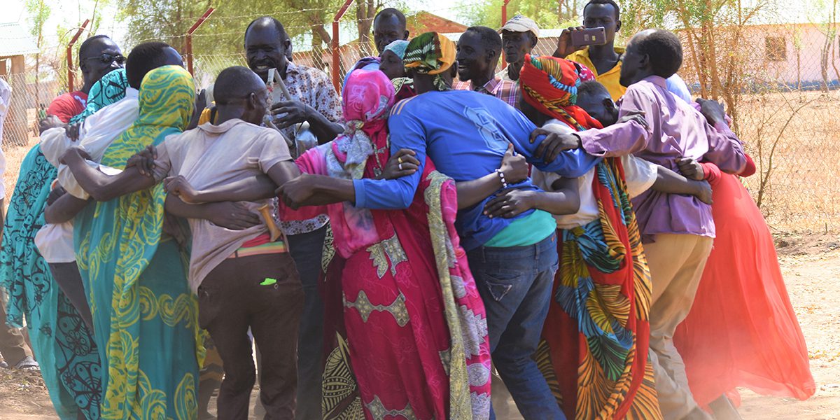 Un groupe d’adulte danse, chante et frappe du pied dans un cercle alors qu’ils se préparent à fêter la Journée internationale de la femme à Maban, Soudan du Sud (Paul Jeffrey/Misean Cara)