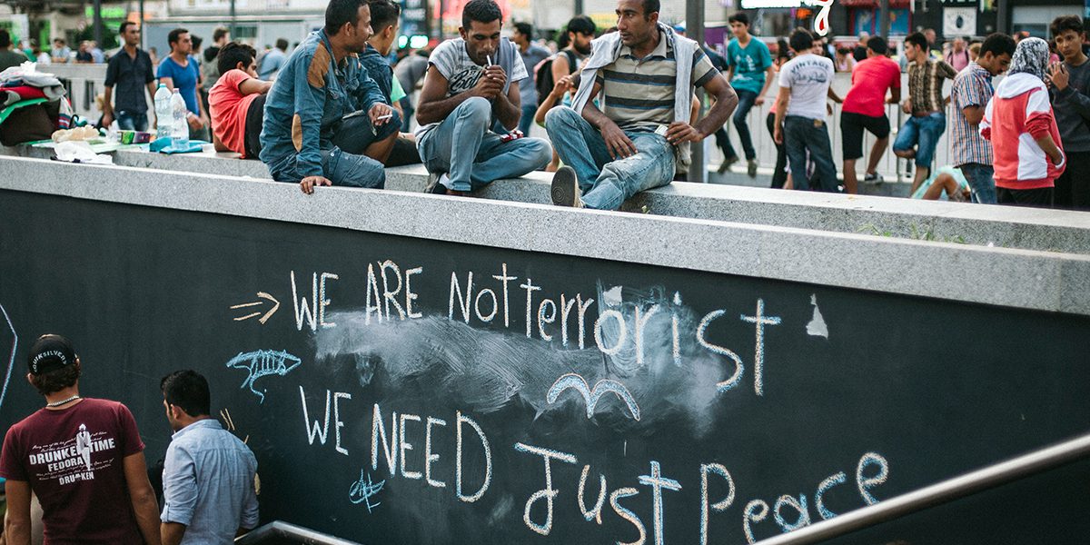 Un texte à la craie, sur un mur où il est écrit : « Nous ne sommes pas des terroristes, nous avons simplement besoin de paix » (Kristof Holvenyi/JRS)