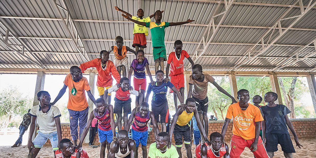 Un grupo de niños forman una pirámide humana en una de las actividades recreativas patrocinadas por el Servicio Jesuita a Refugiados en el Campamento de Refugiados de Doro, en Maban, Sudán del Sur. (Paul Jeffrey / Misean Cara)