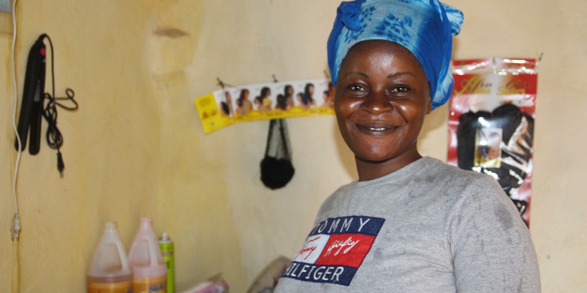 Chimene sonríe orgullosa en su salón de belleza. (Servicio Jesuita a Refugiados)