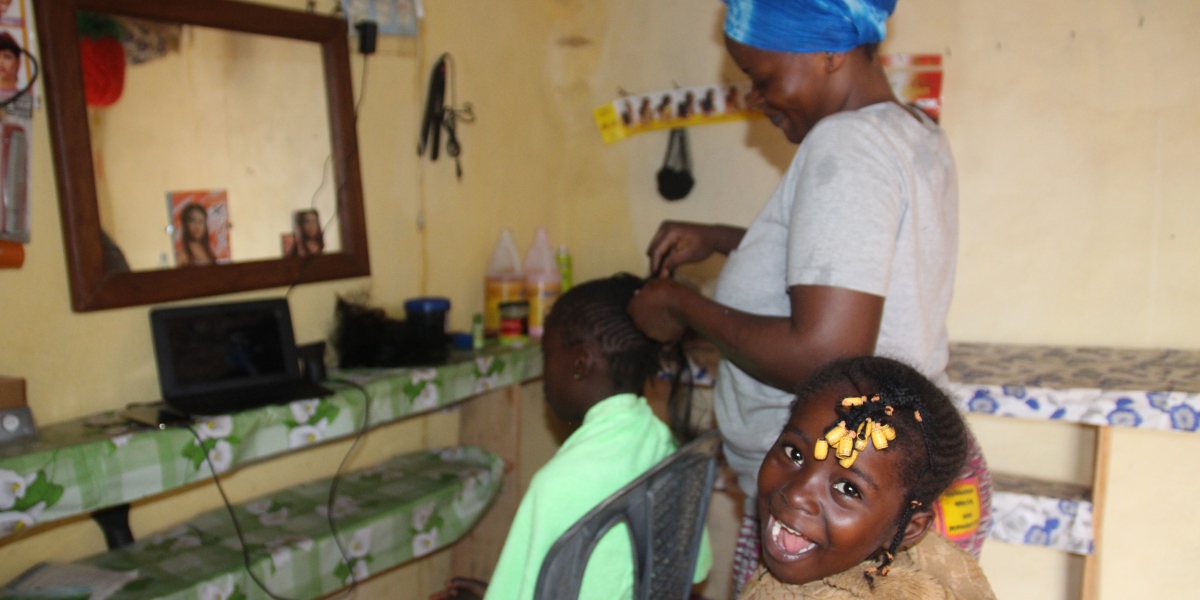 Chimene Steva works on a young girl's hair as another waits for her turn. (Jesuit Refugee Service)