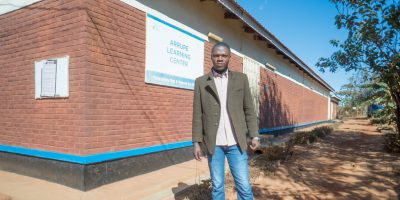 Stany standing outside the Arrupe Learning Center building in Dzaleka refugee camp. (Hugo Mpenzi / JRS Community Journalist)
