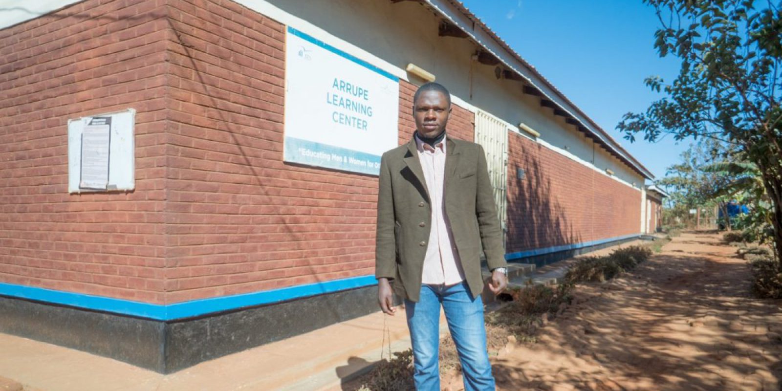 Stany standing outside the Arrupe Learning Center building in Dzaleka refugee camp. (Hugo Mpenzi / JRS Community Journalist)