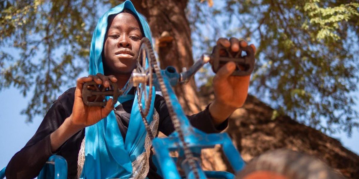 Sadié with her new tricycle, donated by UNHCR and JRS