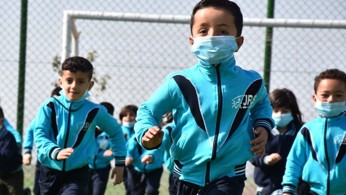 The cover photo of the 2021 AnnuaL Report show children from the JRS Arrupe Kindergarten test the turf of the new JRS Loyola Sports Ground, in Sharya, northern Iraq.