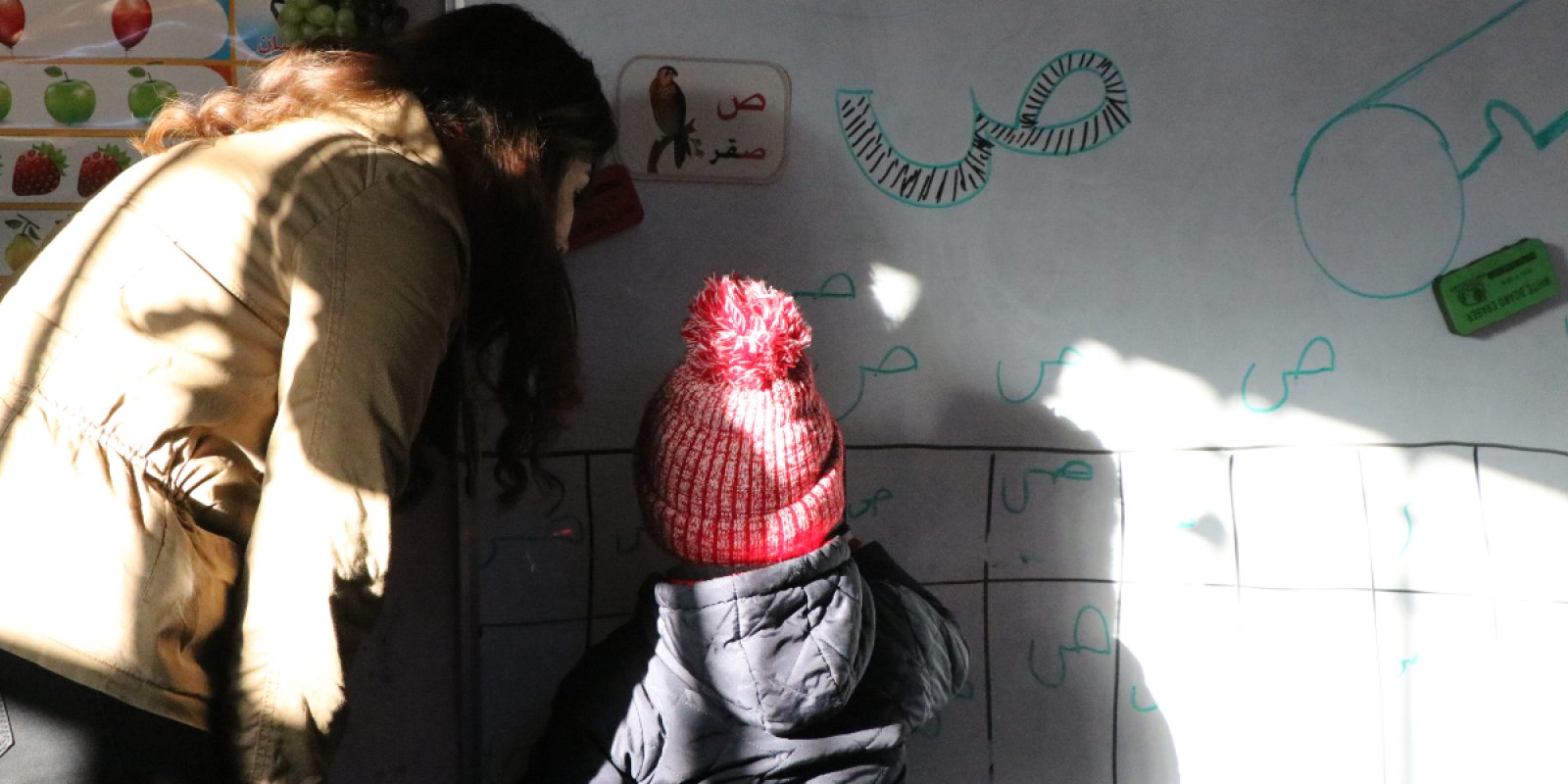 Un profesor da clases a un niño desplazado en la guardería del JRS en Qaraqosh. Para los niños desplazados de Irak, ir a la escuela puede ser un reto. Hoy Jacob y Abdullah han vuelto a la escuela después de varios años.