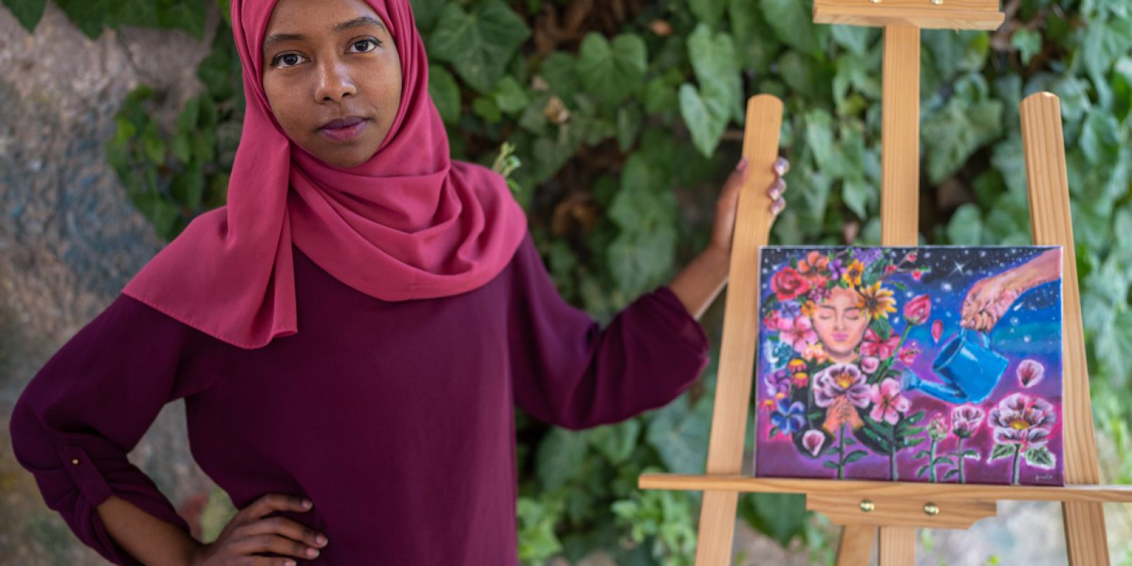 Fowza poses with some of her artwork, at JRS Community Center in Amman. Art for refugees in Jordan is an effective tool for conveying messages and delivering the voice of the voiceless.