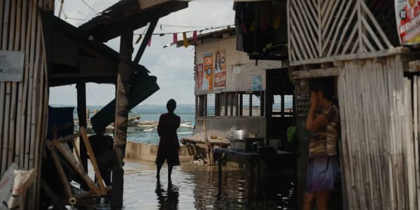 The photo shows stilt houses on the water and community members on Guindacpan Island