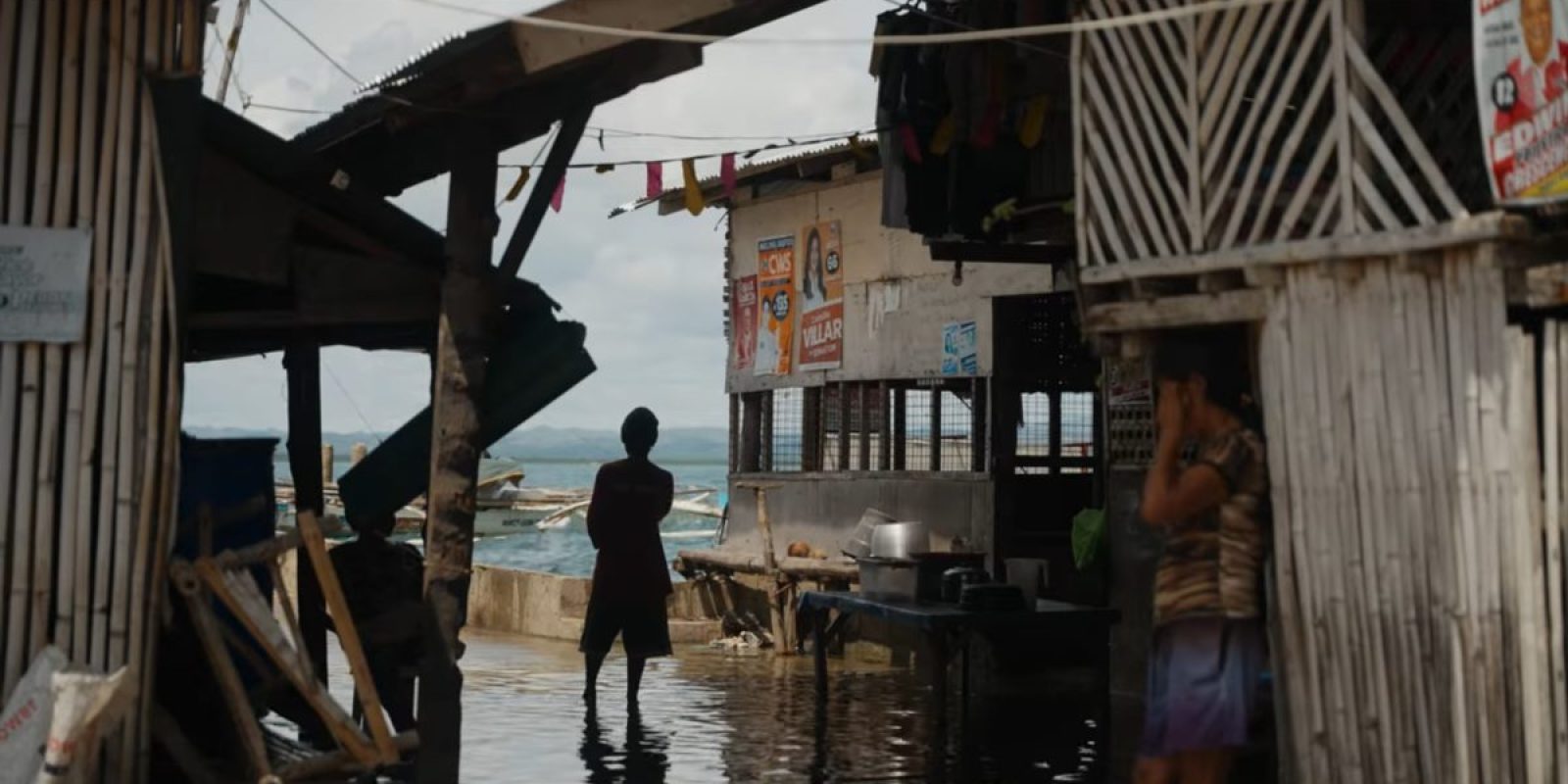 The photo shows stilt houses on the water and community members on Guindacpan Island